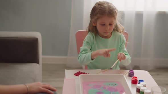 Adorable Little Girl Makes Colorful Pattern on Water Surface