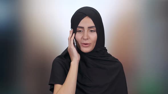 Portrait of a Beautiful Muslim Woman, a Female in a Hijab Communicates and Talks on a Mobile Phone