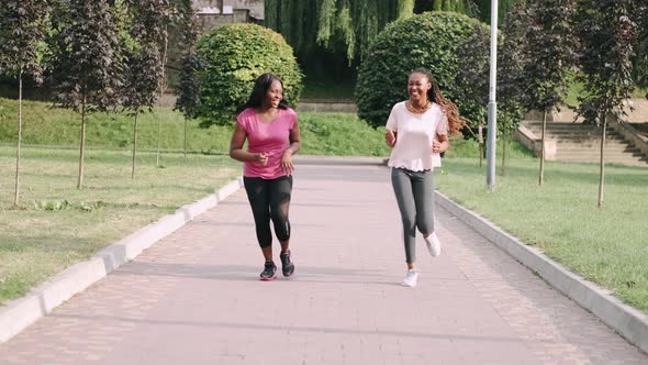 Young Active African American Female Friends Jogging in Park To Keep Healthy