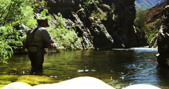 Fisherman fly fishing in river