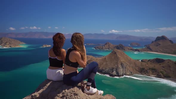 Panoramic Aerial View Two Young Females Sitting on Clifftop and Admiring Landscape of Ocean and
