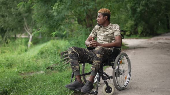 Wide Shot African American Young Military Man in Wheelchair Looking Away Admiring Beauty of Summer