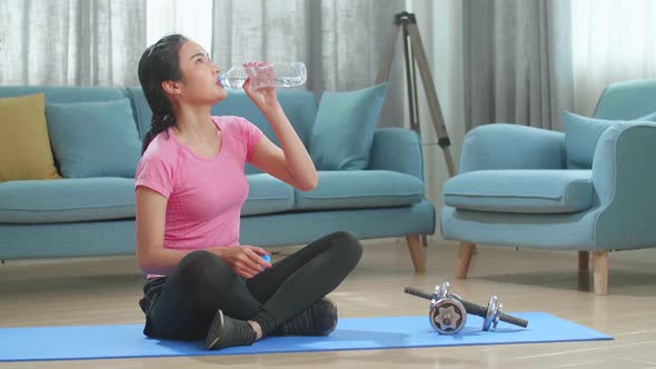 Young Asian Woman Drinking Water And Resting, Having Break After Doing Exercise At Home