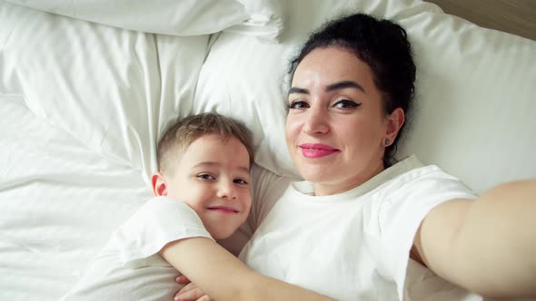 Portrait Happy Cute Funny Cheerful Mom and Son Gently Hugging Daughter with Mom Take Selfie Using