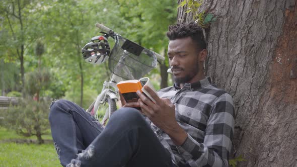 Portrait Handsome Confidient African American Man Sitting Near His Bicycle Under an Old Tree