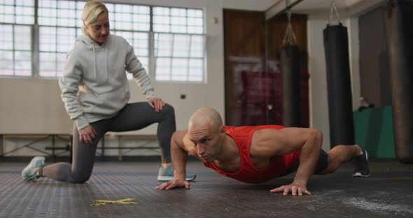 Caucasian muscular man doing push ups with female coach