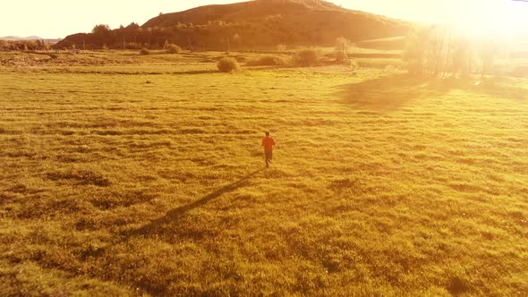 Flight Over Sport Man at Perfect Green Grass Meadow. Sunset in Mountain