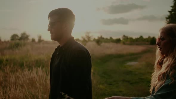 Woman Supporting Young Man Outdoors at Sunset