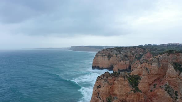 Aerial View of Ocean and Rocky Cliffs in Lagos Portugal Drone Shot with Cloudy Weather