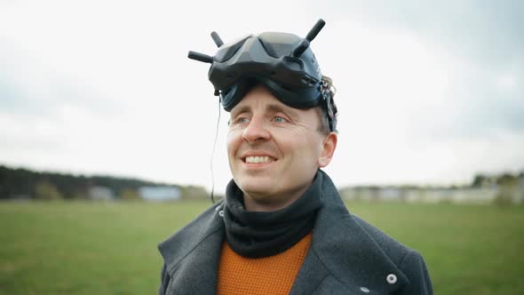 Smiling Man with Black FPV Drone Goggles Over Forehead Looks Away