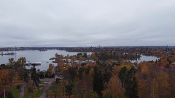 Aerial pan shot of waters of Helsinki with forest trees and cityscape in background. Cloudy day duri