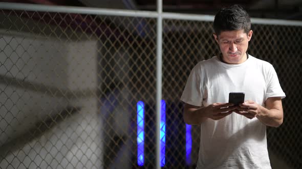 Hispanic Man Wearing Casual Clothing Thinking While Using Phone