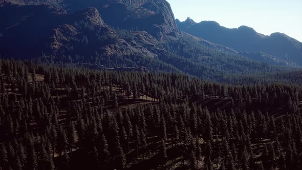 Panoramic Aerial View of Rocky Ridge Among Green Forest at Sunset alt