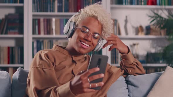 African Woman in Wireless Headphones Holding Mobile Video Call Conversation
