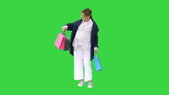 Beautiful Happy Exciting Pregnant Blonde Woman Holding Shopping Bags on a Green Screen, Chroma Key