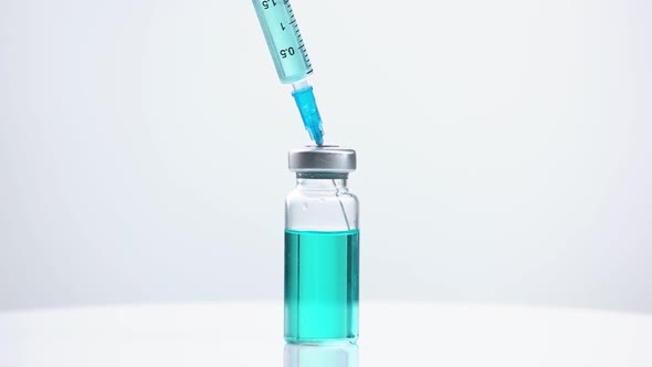 Glass Medicine Vial with Blue Liquid and Syringe.