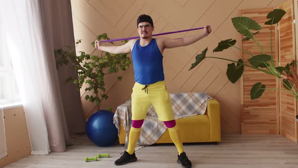 Retro Fitness Man with a Moustache Glasses and Headband in Blue Yellow and Purple Sportswear Doing