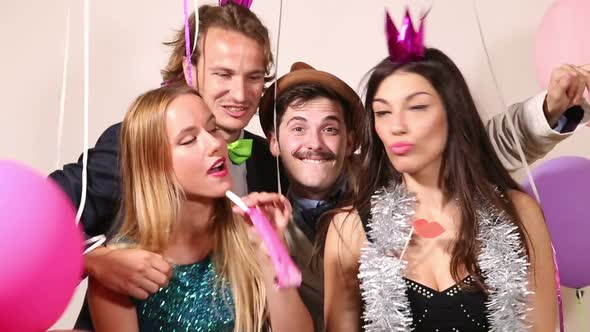 Two cute couples having fun in party photo booth