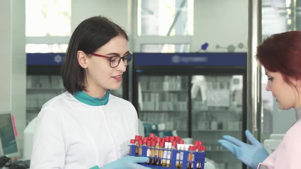 Female Researcher Handing Blood Samples to Her Colleague