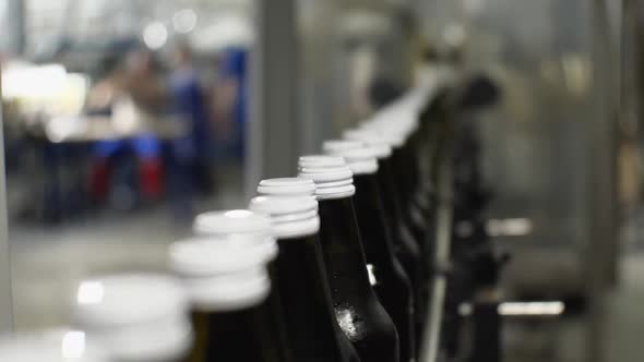 Close-up of glass water bottles on the conveyor Focus on the white lids