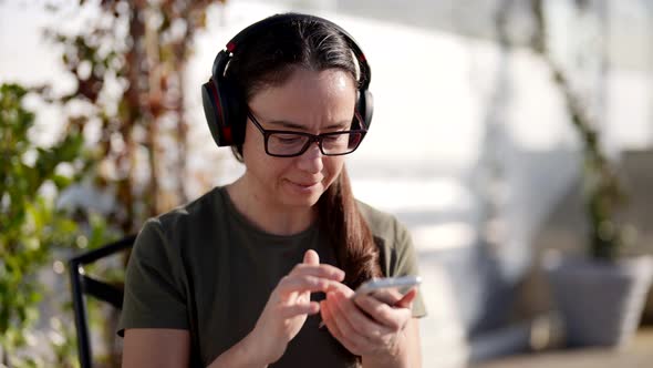 Closeup Portrait of a Happy Mature Woman with a Smartphone Listening to Music in a Wireless Headset