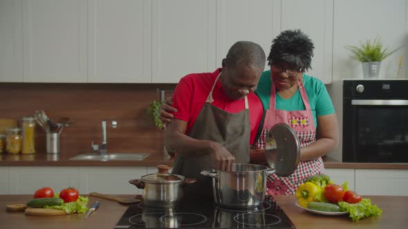 Senior Wife Encouraging Beloved Man Cooking in Kitchen