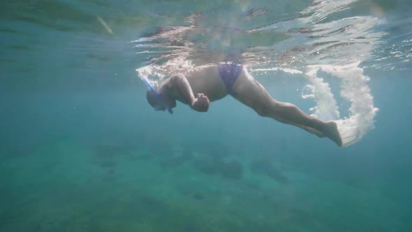 Underwater View of Senior Man in Snorkeling Mask Diving Into the Sandy Seabed.