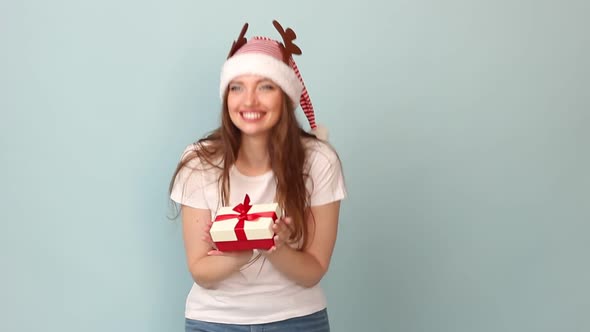 Woman White Tshirt with a Red Santa Claus Hat on a Pastel Blue Background