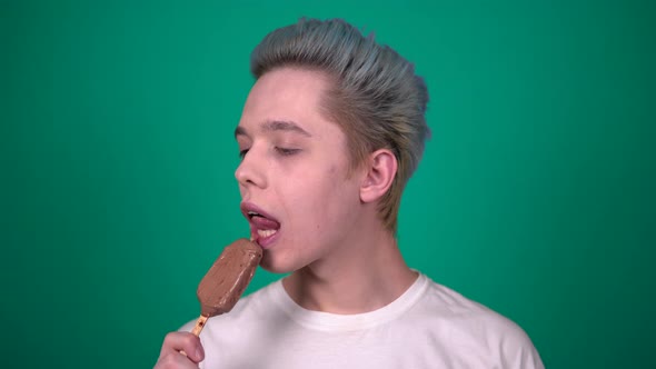 Young Happy Man Eating Chocolate Ice Cream Looking to Camera Portrait