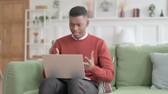 African Man with Laptop Feeling Angry on Sofa