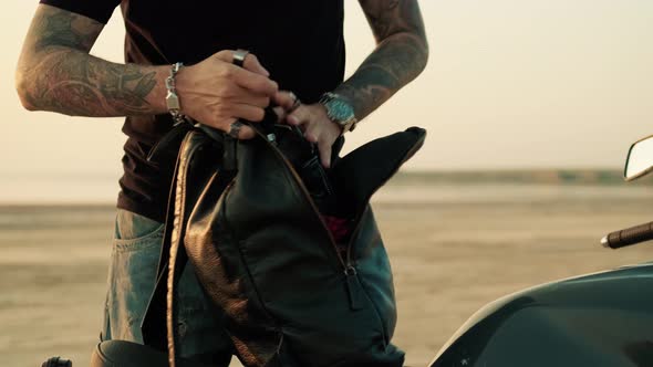 Tattooed biker man holding and using his backpack