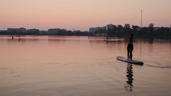 Sunset Woman Silhouette on Lake Stand Up Paddle Board SUP Wide View Futage