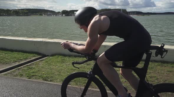 Triathlete Rides a Cutting Bike Pro Cyclist Rides on a Road Near a Lake an Athlete Trains Before a
