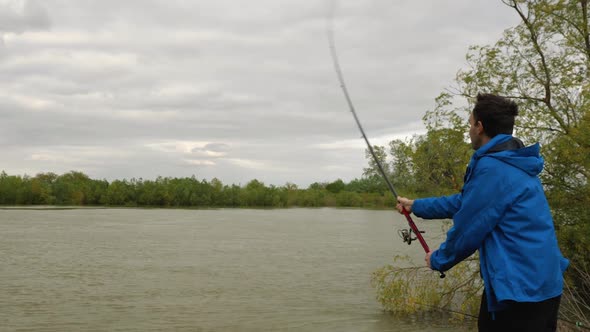 An Angler in a Blue Jacket is Casting a Bait with a Rod