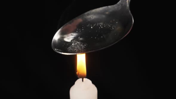 Cooking Heroin on a Spoon Over the Flame of Candle