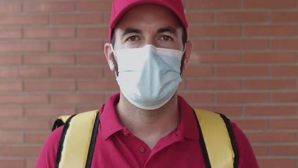 Delivery Young Man in Red Cap Looking at Camera While Wearing Face Mask