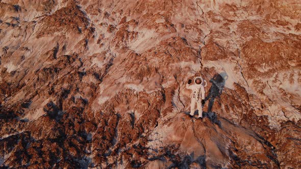 Astronaut Standing on a Rock Waving Hand