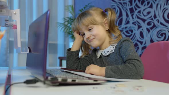 Bored Kid Listening Audio Lesson Studying at Table Using Digital Laptop Computer Doing Homework