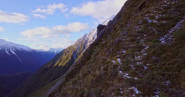 Dramatic aerial flying over the cliff sides of the Southern Alps at Arthur's Pass in New Zealand. On