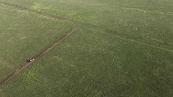 Aerial Video Showing a Small Red Plane Landing on a Field