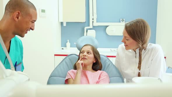 Friendly dentist and her assistant talking with lovely little girl