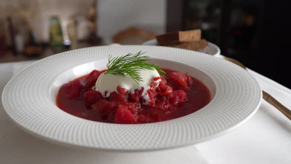 Plate of red beetroot soup borsch rotates on table. Traditional Ukraine food