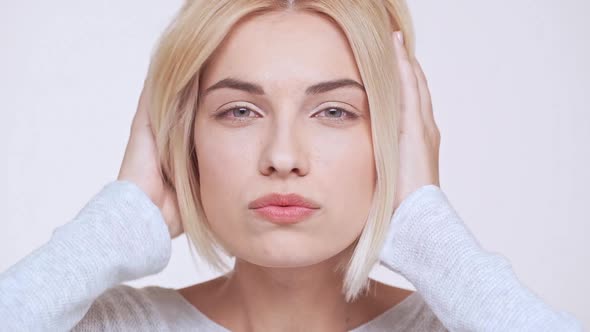 Young Beautiful Blonde Girl Fixing Hair and Make Up Over White Background Slow Motion