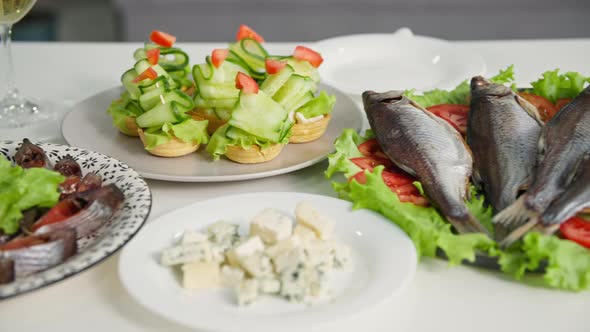 Festive Lunch Delicious and Fresh Seafood and Cheese Cuts on Plates on a White Tablecloth Closeup