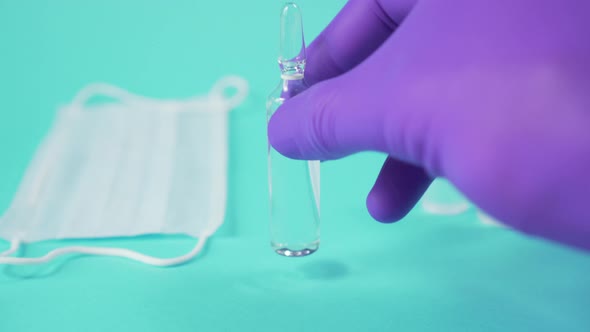 hand in surgical gloves puts a glass ampoule with a vaccine 