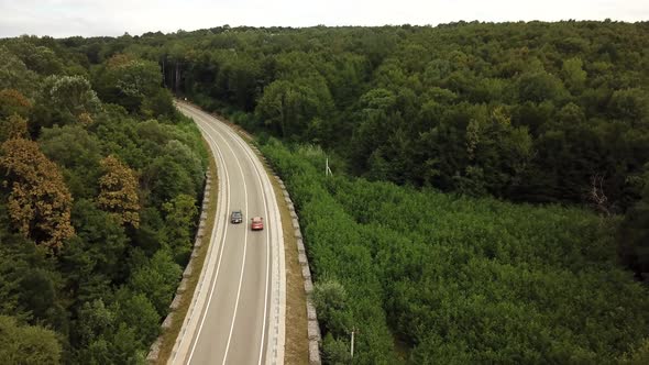 Orange SUV Car Driving on a Rural Road in the Mountains and Forest at Summer Sunny Day - Drone Point