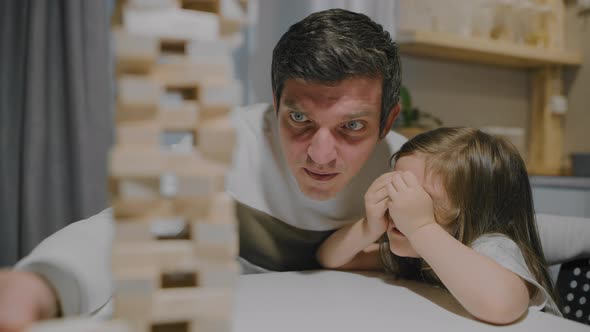 Father and Daughter are Playing a Board Game Made of Wooden Blocks