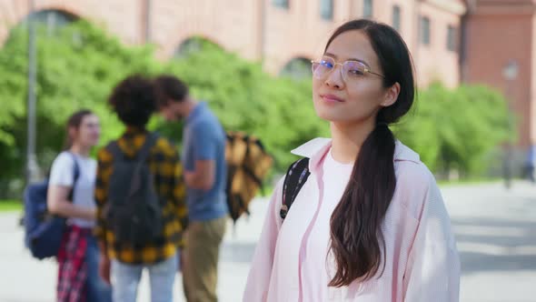 Portrait of Positive Asian Female Student Looking at Camera at College Campus on Sunny Day Outdoors