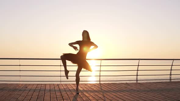 Dancing Ballerina in Black Ballet Tutu and Pointe on Seafront Above Ocean or Sea