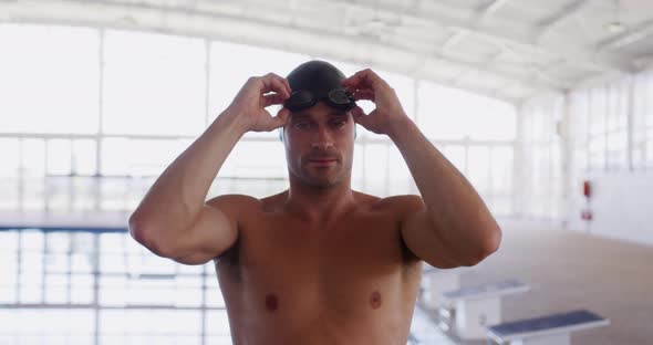 Swimmer taking off his pool goggles and looking at camera